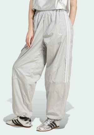 Lichtgrijze joggingbroek van een gladde, lichte stof; voorzien van een elastische tailleband, witte zijstrepen en taps toegesneden enkels.