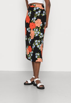 Saia midi preta com estampado floral, apresentando grandes rosas laranja e pequenas flores azuis, confeccionada em tecido leve. Combinada com sandálias brancas.