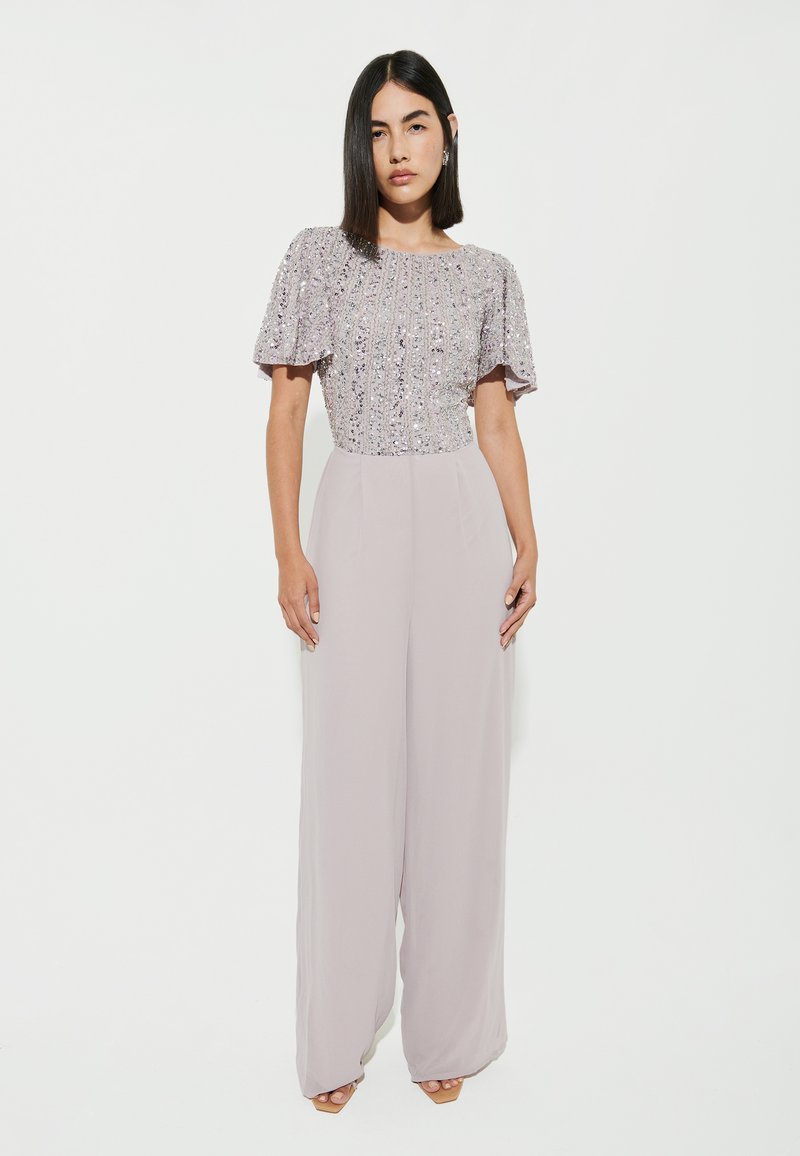 Jumpsuit lilla chiaro con top di paillettes e maniche a farfalla corte, design a gamba larga, realizzato in tessuto liscio e fluido.