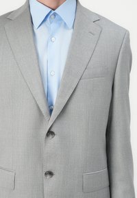Light gray suit jacket with a subtle pinstripe pattern, single-breasted, two front pockets, and a notched lapel, worn over a light blue shirt.