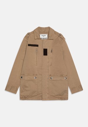 Khaki kurtka z kołnierzem, zapinana na zamek i napy, z elastycznymi mankietami. Posiada fakturowaną naszywkę na piersi oraz naramienniki na ramionach.