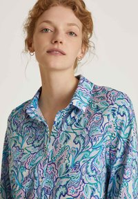 Camicia con bottoni in tessuto leggero, caratterizzata da un motivo paisley colorato e intricato nelle tonalità di blu, verde e rosa. Il colletto è arrotondato.