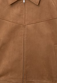 Veste en suede marron avec fermeture éclair à l'avant, grand col et deux poches latérales. Présente des détails de coutures subtils et une texture lisse.