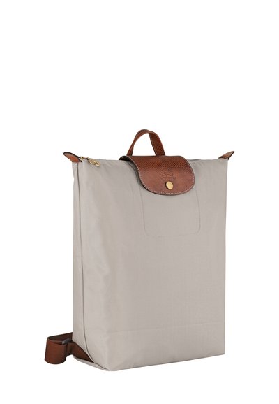 Beiger Rucksack aus strapazierfähigem Stoff mit einer strukturierten braunen Lederklappe und einem Griff. Verfügt über einen goldenen Reißverschluss und ein schlichtes Design.