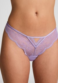 Lavendel kant string met een gladde stoffen voorkant, voorzien van een driehoekige uitsparing en gegolfde randen langs de tailleband en beenopeningen.