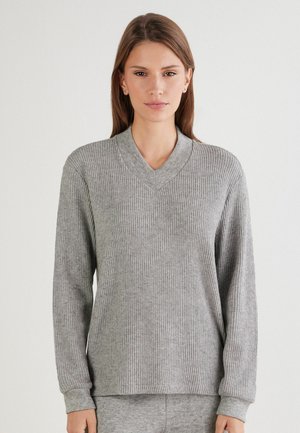 Pull en tricot côtelé gris avec un col en V, des manches longues et des poignets. Texture douce, coupe décontractée et motif subtil sur l'ensemble du tissu.