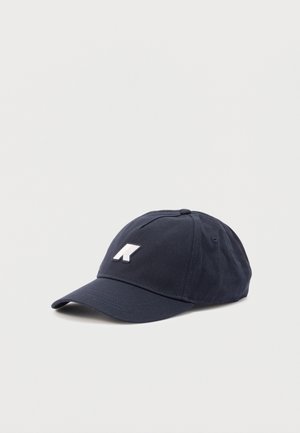 Mørkeblå baseballkasket med buet skygge og hvidt, stiliseret "K" logo foran mod en ensfarvet lys baggrund.