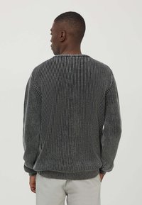 Maglione grigio con texture e lavorazione a coste verticali, colletto rotondo e maniche lunghe. Tessuto morbido con una vestibilità comoda e polsini ed orlo elastici.