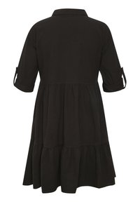 Schwarzes, knielanges Kleid mit Kragen, kurzen aufgerollten Ärmeln und einem mehrlagigen Rüschensaum. Hergestellt aus leichtem Stoff mit glatter Textur.