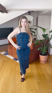 Denimkjole med tynne stropper, tettsittende design og synlige sømmer. Modellen har på seg mørkerøde sandaler. Innendørs med potteplante i bakgrunnen.