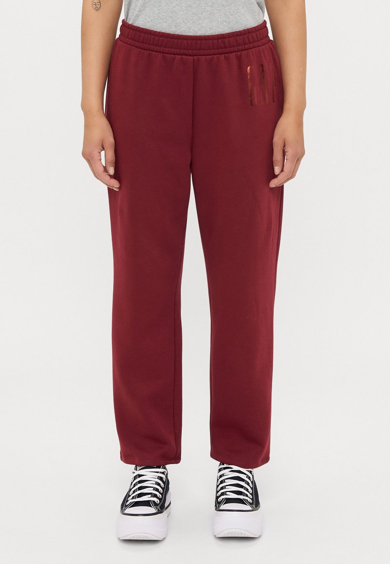 Pantaloni della tuta bordeaux con vita elastica, tasche laterali e una piccola striscia verticale a sinistra. Tessuto in misto cotone.