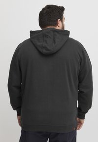 Felpa nera in cotone con tasca a marsupio, cappuccio regolabile con coulisse e polsini a coste, caratterizzata da un piccolo tag con logo sull'orlo.