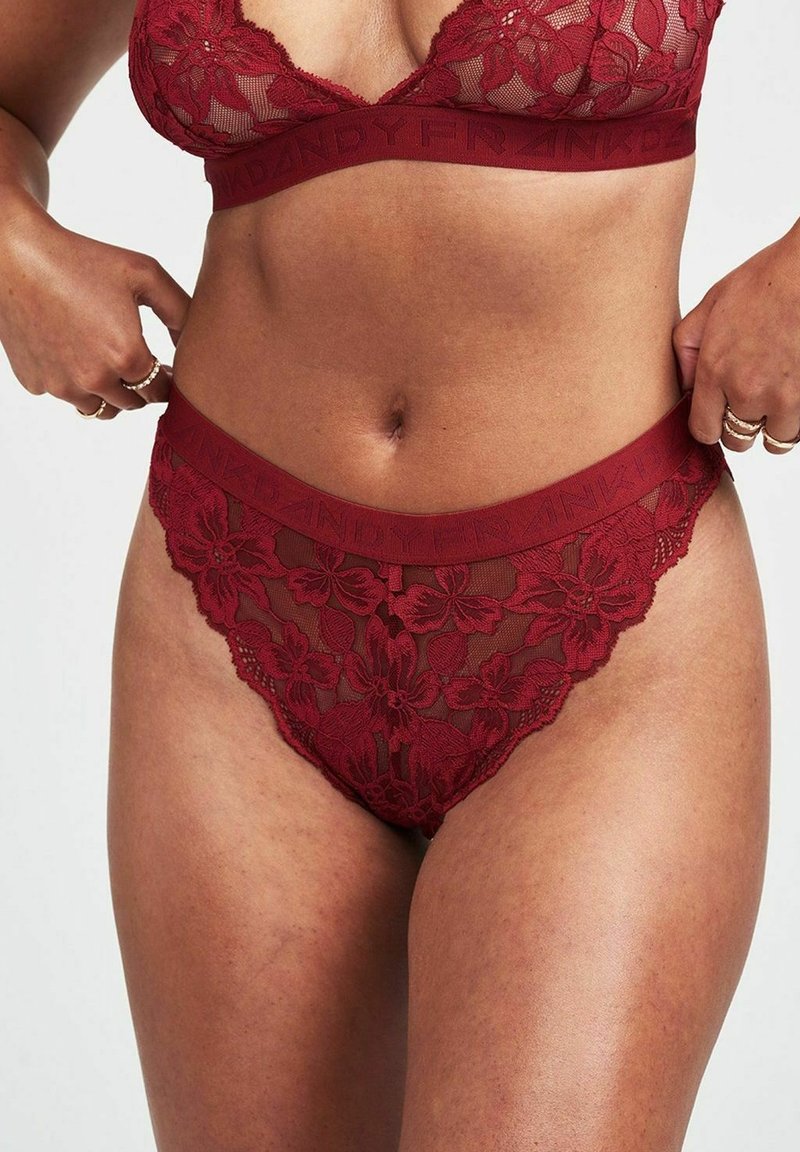 Bordeaux kanten lingerieset met een bloemmotief. De beha heeft een driehoekige vorm met doorzichtig materiaal, en de tailleband is breed en met een logo versierd.