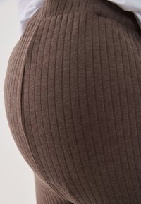 Brown ribbed leggings made from soft fabric, featuring textured stripes and a high waist design for a snug fit.