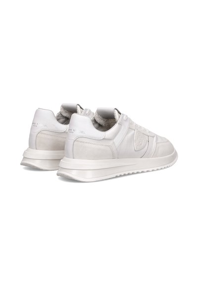 Hvide sneakers med en blanding af glat læder og ruskindsteksturer, der har en polstret krave, snørebånd foran og en tykk gummisål.