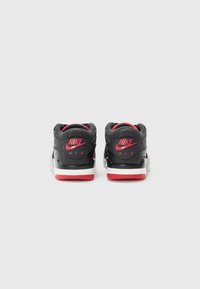 Schwarze und rote High-Top-Sneakers aus glattem Synthetikmaterial, gepolsterter Knöchel, ikonisches Logo an der Ferse und eine weiße Mittelsohle mit roter Außensohle.