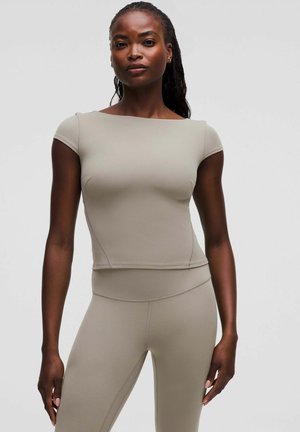 Beige eng anliegendes Oberteil mit kurzen Ärmeln und viereckigem Ausschnitt, aus elastischem Material. Nahtdetails entlang der Seiten und am Saum.