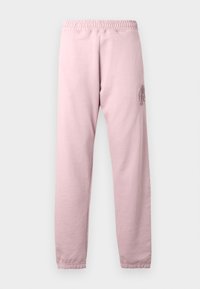 Calças de treino rosa claro com cintura elástica e punhos canelados. Apresentam um design floral texturizado na coxa esquerda. Tecido macio.