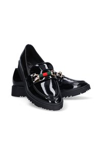 Mocasines de charol negro con un tacón bajo y grueso, que cuentan con un adorno de cadena dorada y una franja verde-roja-verde en una banda frontal.