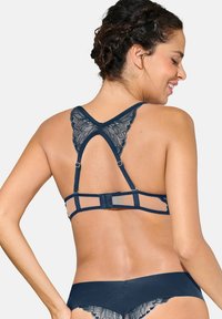Bralette en dentelle bleu marine avec un design de dos en forme de papillon, des bretelles réglables et une bande lisse pour un maintien sûr.