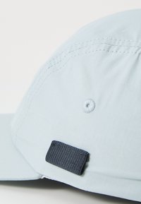 Light blue cap made of lightweight fabric, featuring a rounded top, stitched details, and a dark blue adjustable strap on the back.