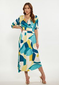 Abito con un motivo astratto colorato in blu, giallo e bianco; presenta un scollo a V, maniche a palloncino e una vita arricciata. Tessuto morbido.