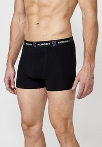Fekete pamut boxer alsónadrág rugalmas derékrésszel, melyen a "KOROSHI" márkaneve és egy szürke koponya logó található. Karcsú szabású kialakítás.