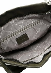 Olive green leather bag interior with gray fabric lining featuring a geometric pattern. Includes a zippered pocket and a brand label.