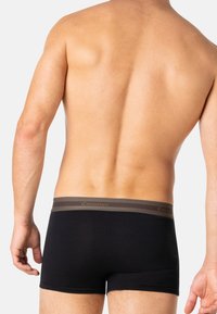 Caleçon noir en matériau doux, avec une ceinture contrastante ornée de deux rayures horizontales marron et gris.