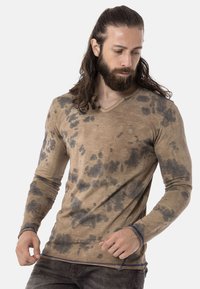 Beige Longsleeve-Shirt mit V-Ausschnitt und dunklen Spritzmustern. Verfügt über einen gerippten Halsausschnitt und Bündchen sowie kontrastierende blaue Nähte.