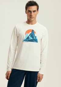 Long-sleeve cream t-shirt featuring a colorful mountain graphic with a sun. Made from soft fabric, with a crew neck and relaxed fit.