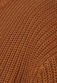 Tissu tricoté de couleur terre cuite riche, présentant un motif en chevrons avec un fil texturé et épais pour plus de chaleur et de profondeur.