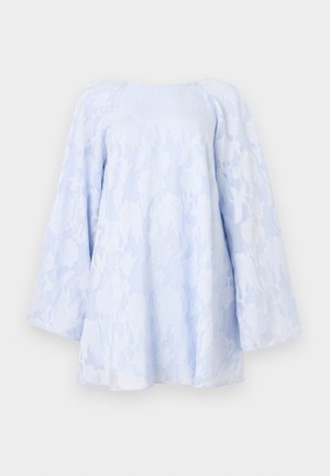 Blouse bleu clair avec superposition en dentelle florale, manches longues et coupe décontractée. Présente un col rond et une surface texturée.
