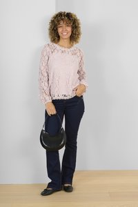 Krajkový top v světle růžové barvě s dlouhými rukávy a vlnkovaným výstřihem, doplněný tmavě modrými rozšířenými džíny a malou černou kabelkou.