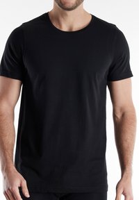 Camiseta de manga corta negra hecha de algodón. Presenta un escote redondo y un corte recto con una textura suave; sin patrones ni gráficos visibles.