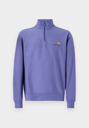 Sudadera de forro polar morada con media cremallera, puños y dobladillo de canalé. Presenta un pequeño logo amarillo y el nombre de la marca en el pecho. Textura suave.