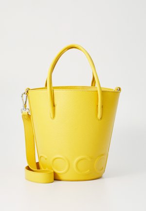 Bolso de mano redondo de cuero amarillo con dos asas, correa para el hombro desmontable y detalle de logo en relieve en la parte frontal.