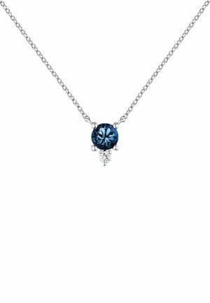 Collar de cadena de plata con una gema azul ovalada en el centro, acentuada por una pequeña piedra clara debajo. Textura suave y acabado pulido.