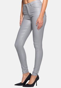 Graue, enganliegende Hosen aus einem eleganten Material mit glatter Textur. Mit Knopfverschluss und einer Naht entlang der Seiten.