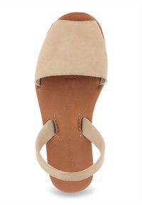 Sandale en suède beige avec une large bride au niveau des orteils, une fine bride à la cheville et une semelle intérieure en cuir beige, mettant en avant un design minimaliste et ouvert.