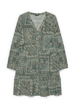 Robe verte à manches longues avec décolleté en V, motifs paisley et tourbillons disposés en carrés, ourlet à volants.