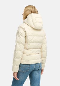 Beige pufferjack met een afneembare capuchon. Heeft een quilted ontwerp, zijzakken en een logo-accent op de linker mouw. Zachte, gladde textuur.