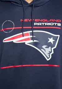 Sweat à capuche bleu marine avec le logo des New England Patriots, des rayures rouges et blanches, et le texte « New England Patriots » en rouge et blanc.