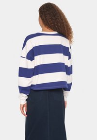 Gestreiftes Langarmoberteil aus Baumwolle in Marineblau und Weiß, mit lockerer Passform und cropped Design. Gerippter Ausschnitt und Bündchen.