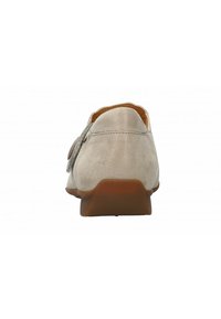 Zapato textil beige con un tacón bajo, diseño sencillo y un acento lateral. Presenta una textura suave y una puntera redondeada.