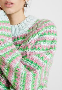 Jersey de punto en rayas pastel de rosa, verde y blanco con un diseño texturizado y grueso y un cuello de canalé.