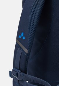Navy backpack strap featuring textured fabric, breathable mesh, blue accent logo, gray stripe, and adjustable buckle for secure fastening.