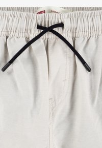 Beige shorts med elastisk midja, som har en svart dragsnodd för justering. Diskret sömdetalj längs sömmarna.