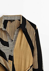 Langärmliges Hemd mit durchgehenden schmalen vertikalen Streifen in Schwarz, Beige und Weiß, mit spitzem Kragen und kontrastierenden Einsätzen.