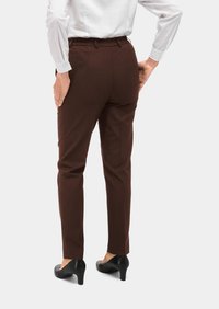 Bruine op maat gemaakte broeken met een elastische tailleband, slim fit en een gladde textuur. G gedragen met zwarte hakken.